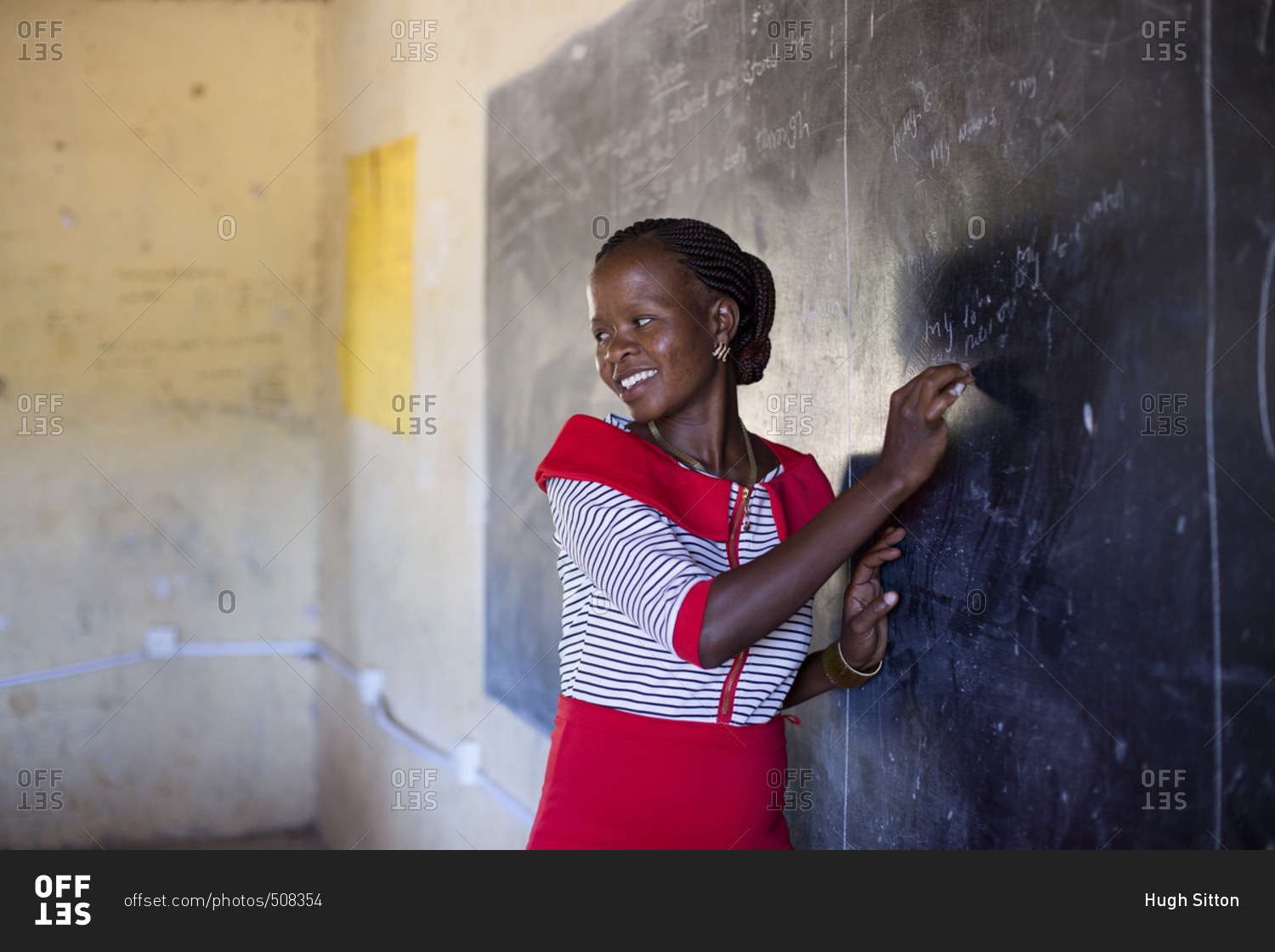 Teacher writing on chalkboard in classroom, Kenya stock photo - OFFSET