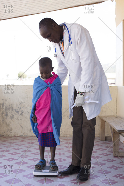 Doctor weighing young girl from Maasai tribe, Kenya, Africa