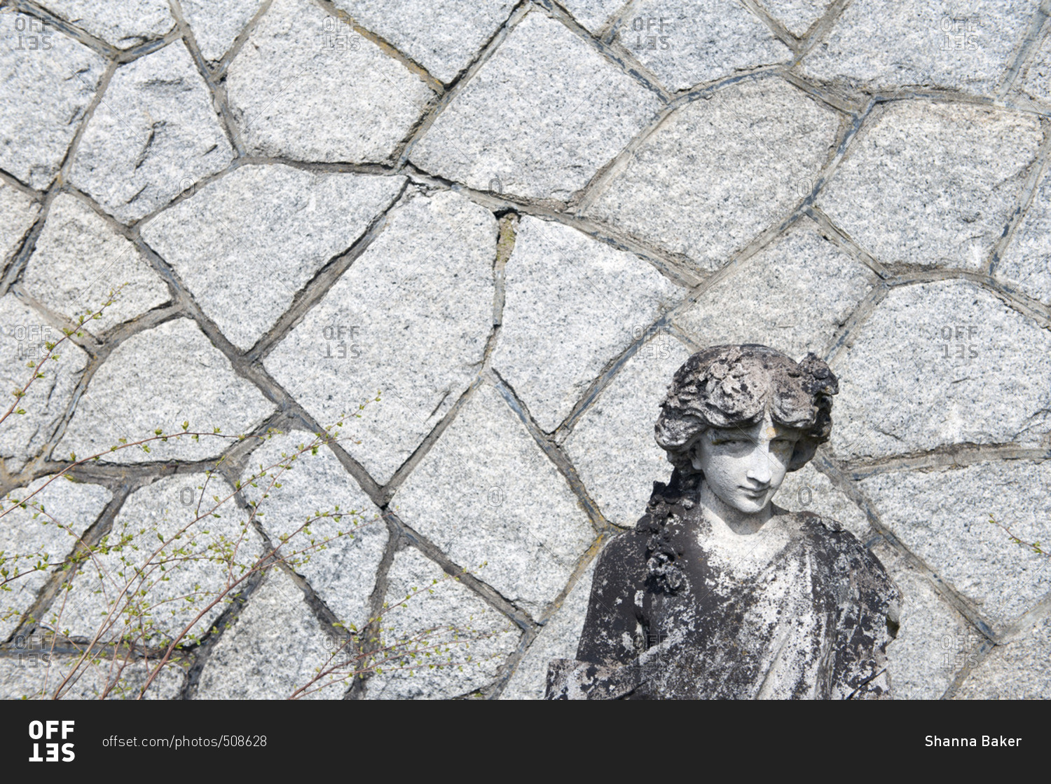 Weathered statue against stone wall