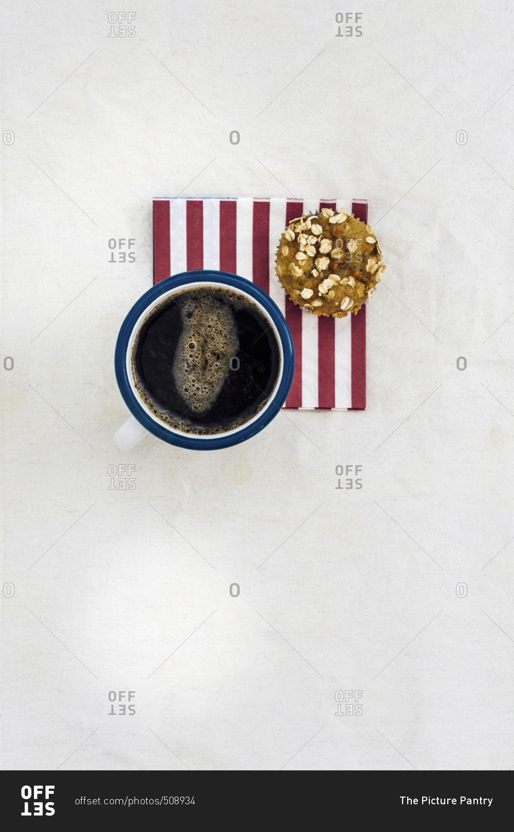 A mug of coffee and a carrot muffin on a red striped napkin photographed from top view.