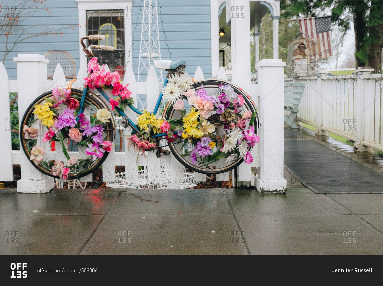 Bicycle decorated with flowers hanging on white picket fence outside home in a small town in Washington