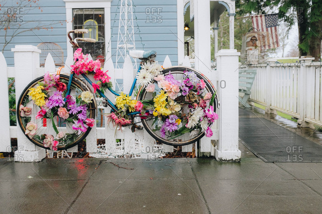 Bicycle decorated with flowers hanging on white picket fence outside home in a small town in Washington