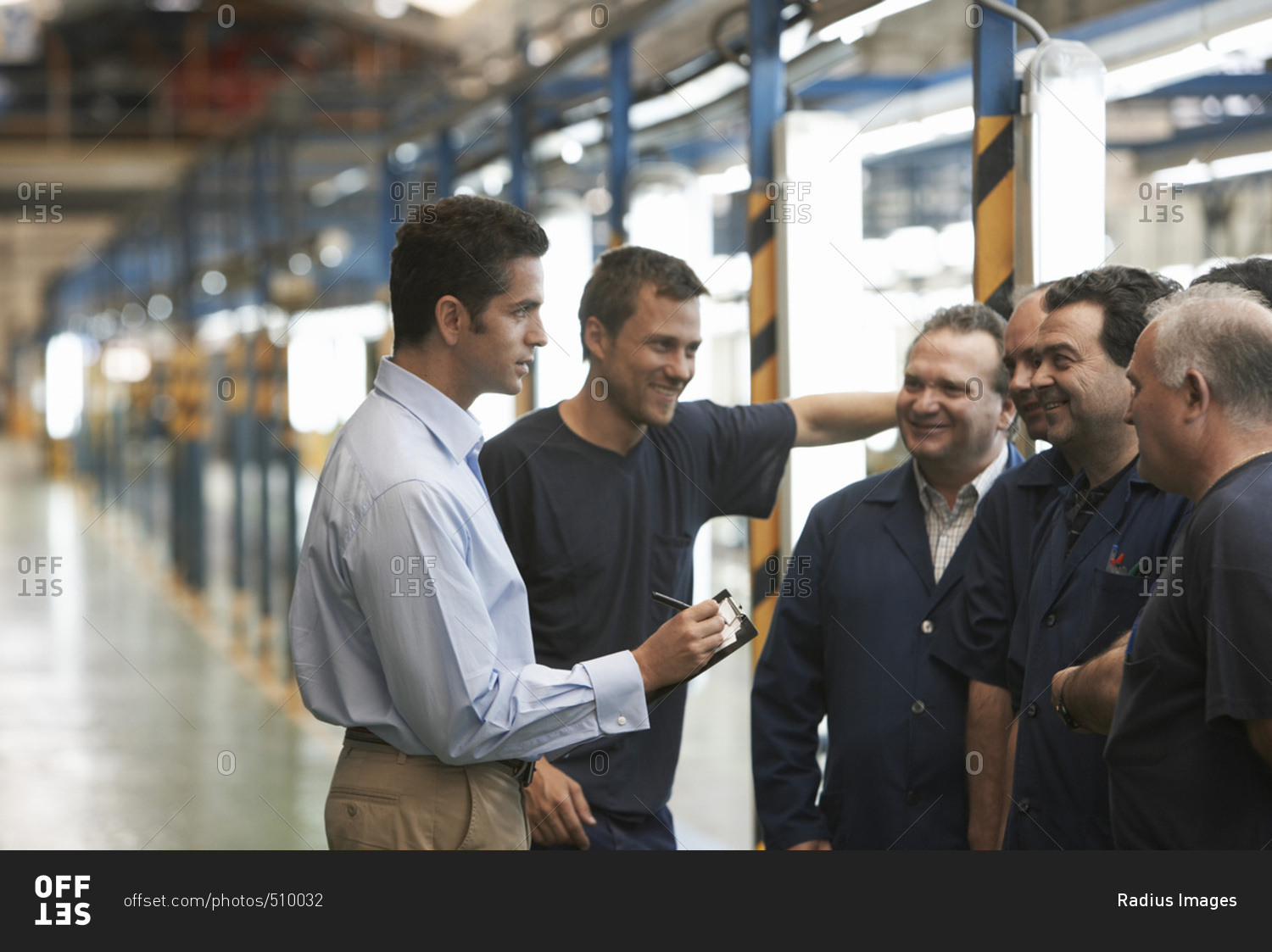 Man Talking to Workers in Automotive Plant