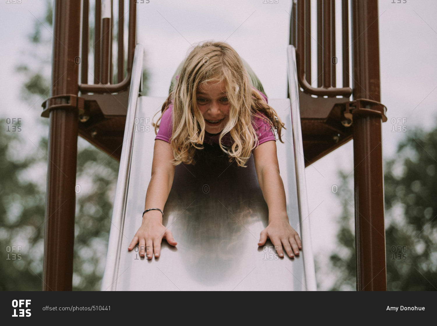 Little girl going down a slide head first stock photo OFFSET