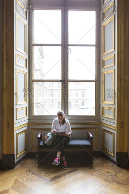 Caucasian teenage girl studying in ornate window at Louvre Museum, Paris, Ile De France, France