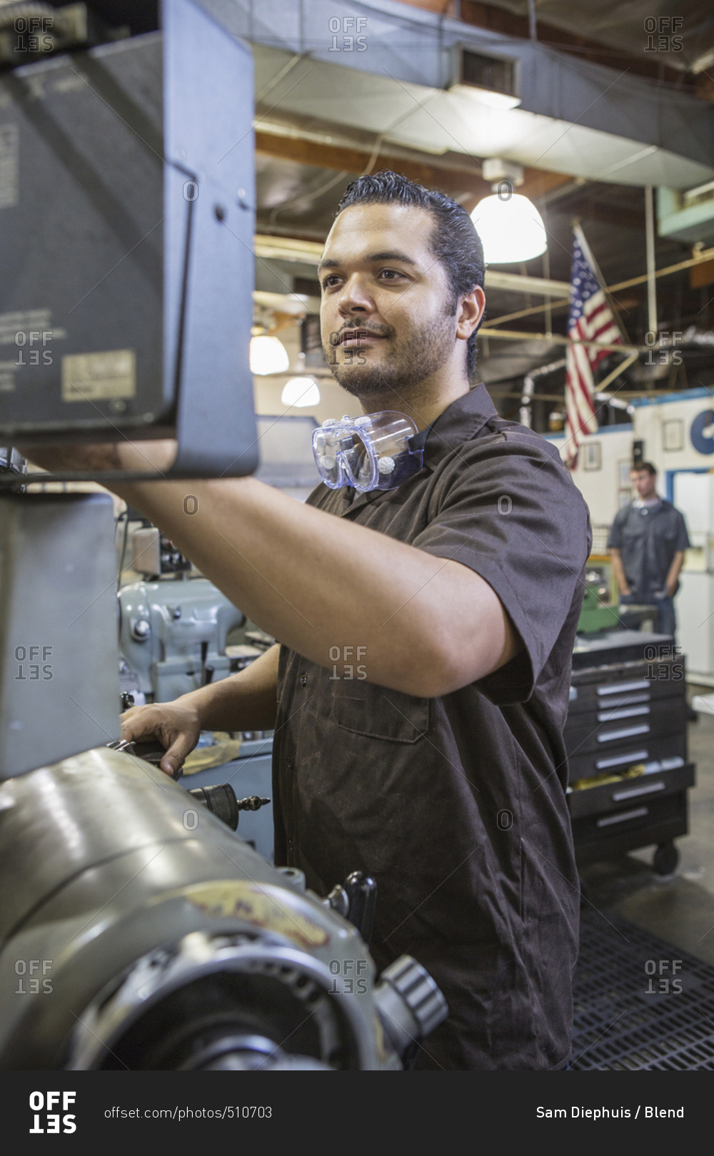 Hispanic worker operating machinery in factory