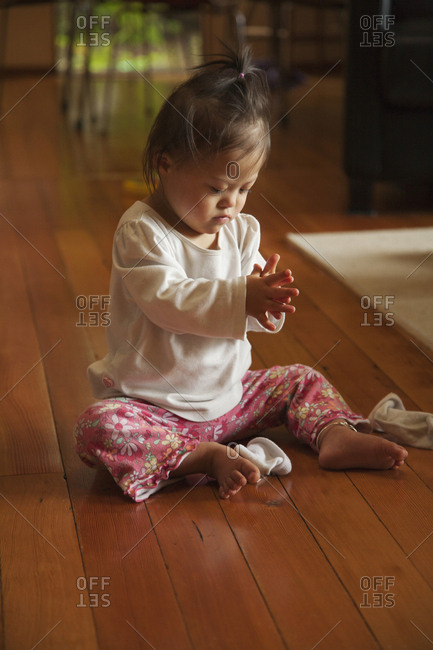 Mixed race baby with Down syndrome playing on floor