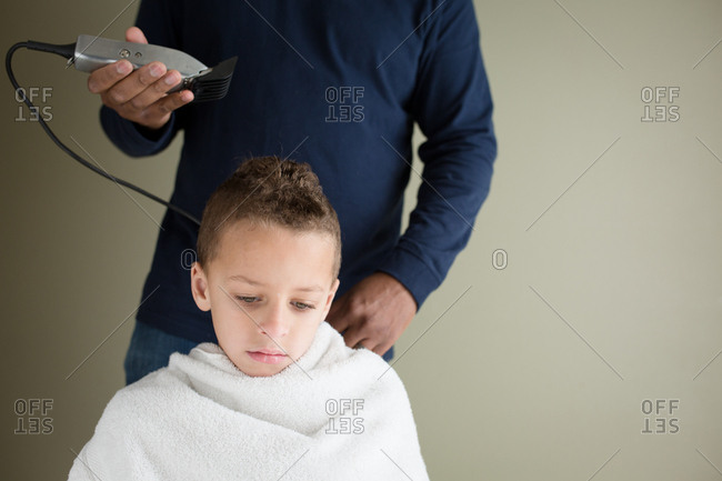 Boy getting a haircut at home about to have clippers used to shave his hair