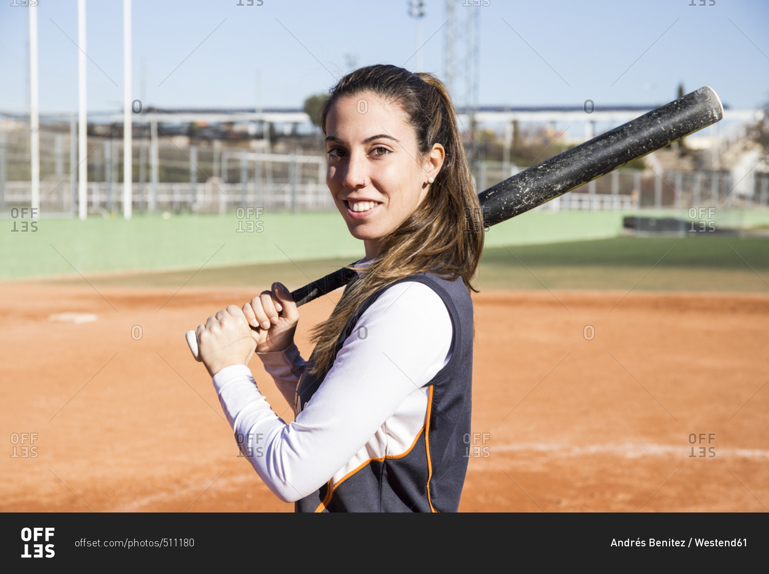 Portrait of smiling female baseball player with a baseball bat