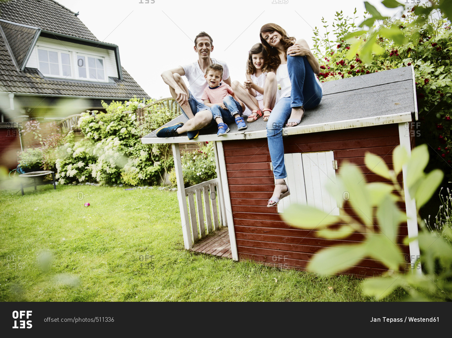 Happy family sitting on roof of their garden shed