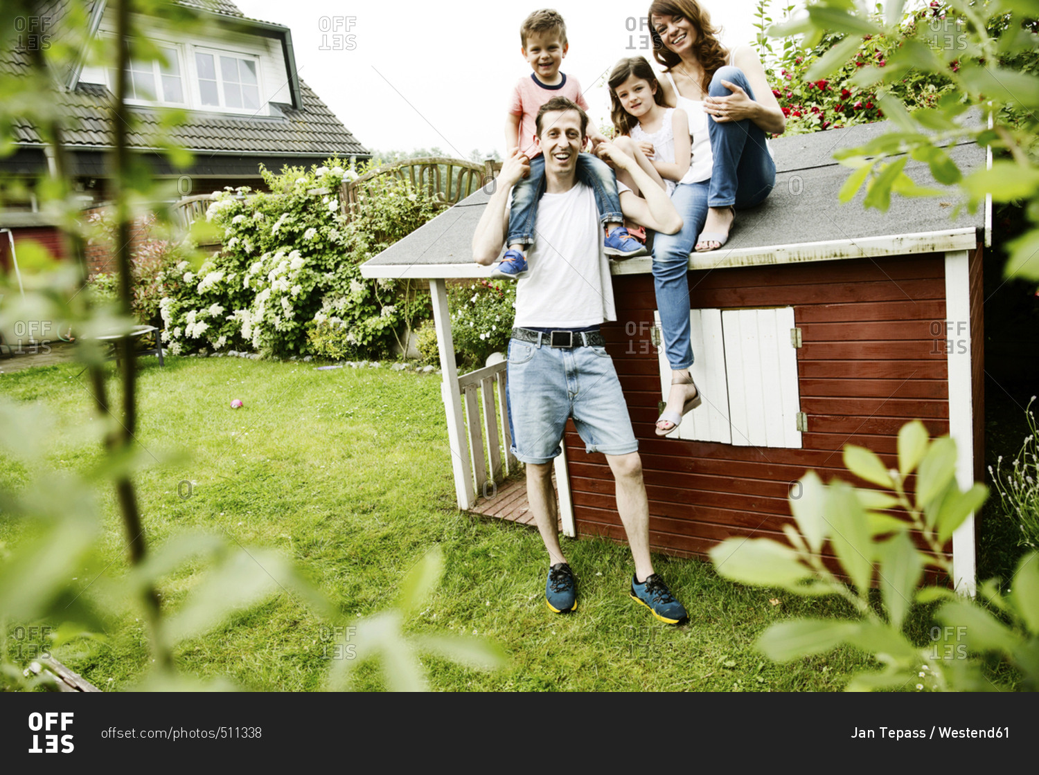 Happy family sitting on roof of their garden shed