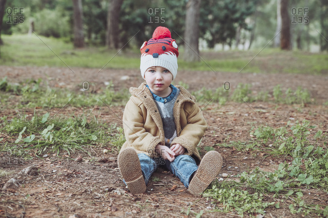 Portrait of boy wearing wooly hat sitting in forest