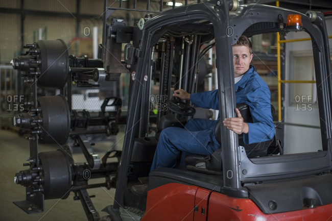Factory working driving a fork lift in warehouse