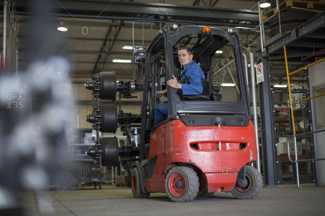 Factory working driving a fork lift in warehouse