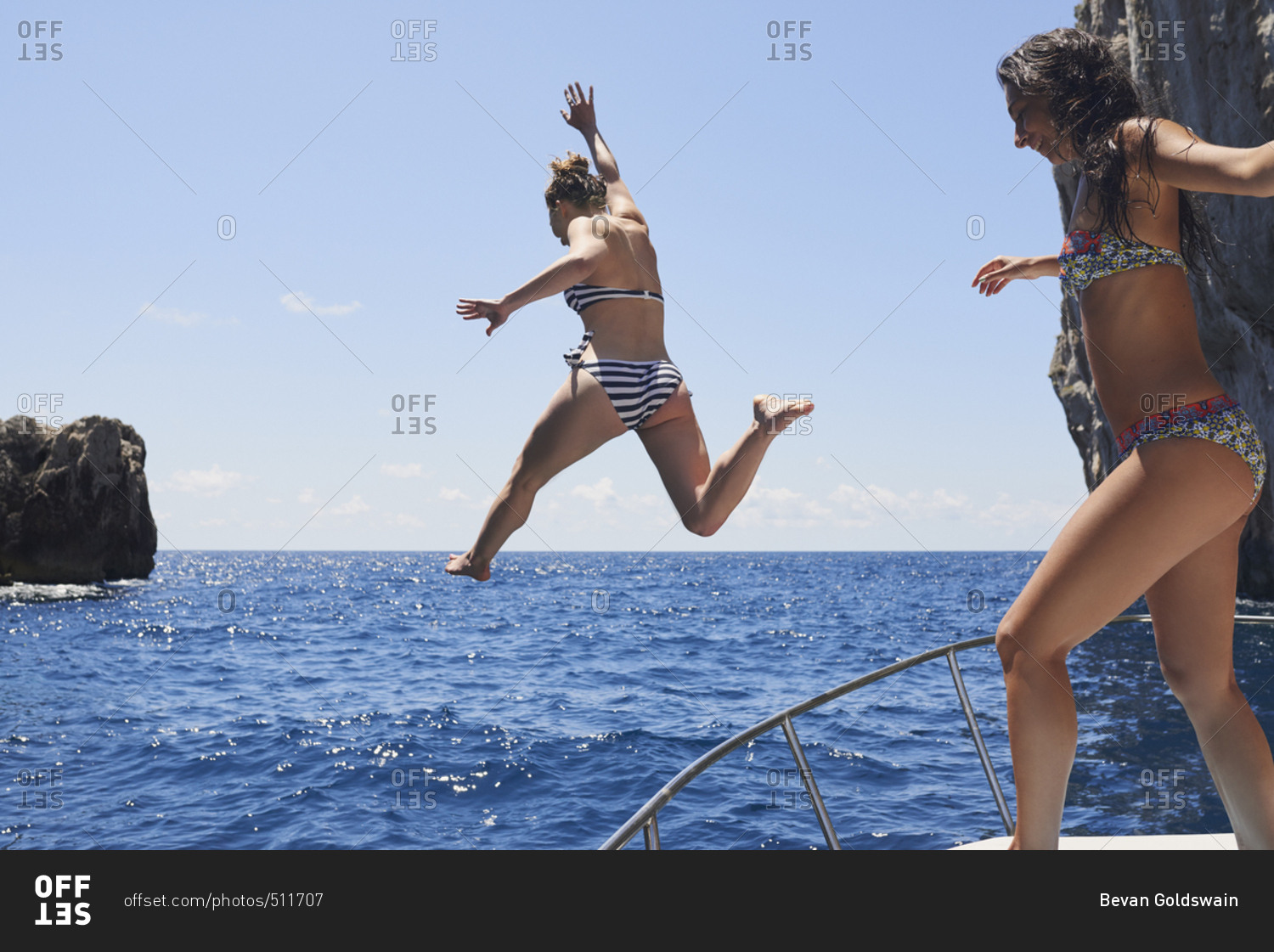 Beautiful Girl Friends jumping into deep blue sea from boat wild free healthy lifestyle on fun travel adventure vacation