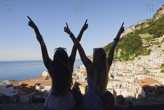 Beautiful happy tourist girl friends enjoying scenic view of Amalfi Coast on summer adventure vacation