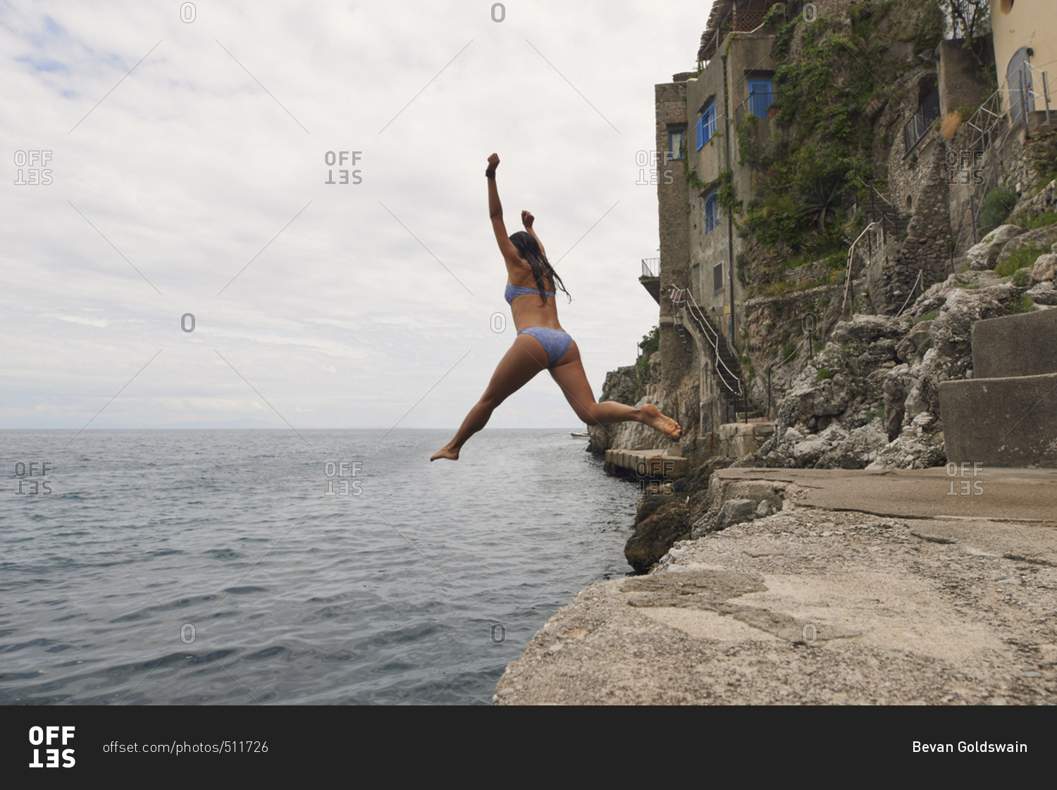 Beautiful girl  jumping into ocean having excitement freedom fun action healthy travel vacation adventure
