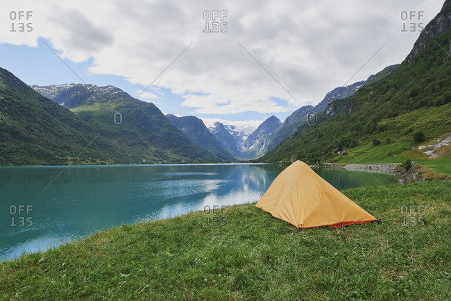 Adventure scene Tent pitched at beautiful lake in view of majestic mountain inspiration wanderlust escape nobody