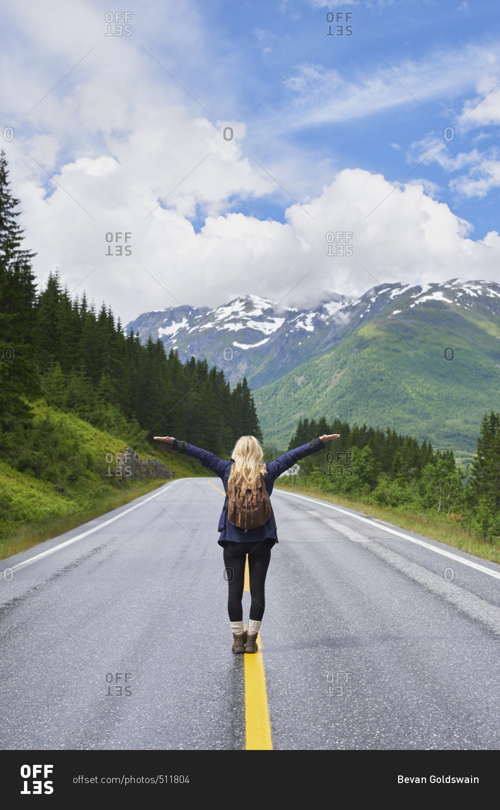 Travel adventure woman celebrates arms raised  at view of majestic road landscape on exploration discover beautiful earth