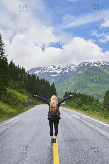 Travel adventure woman celebrates arms raised  at view of majestic road landscape on exploration discover beautiful earth