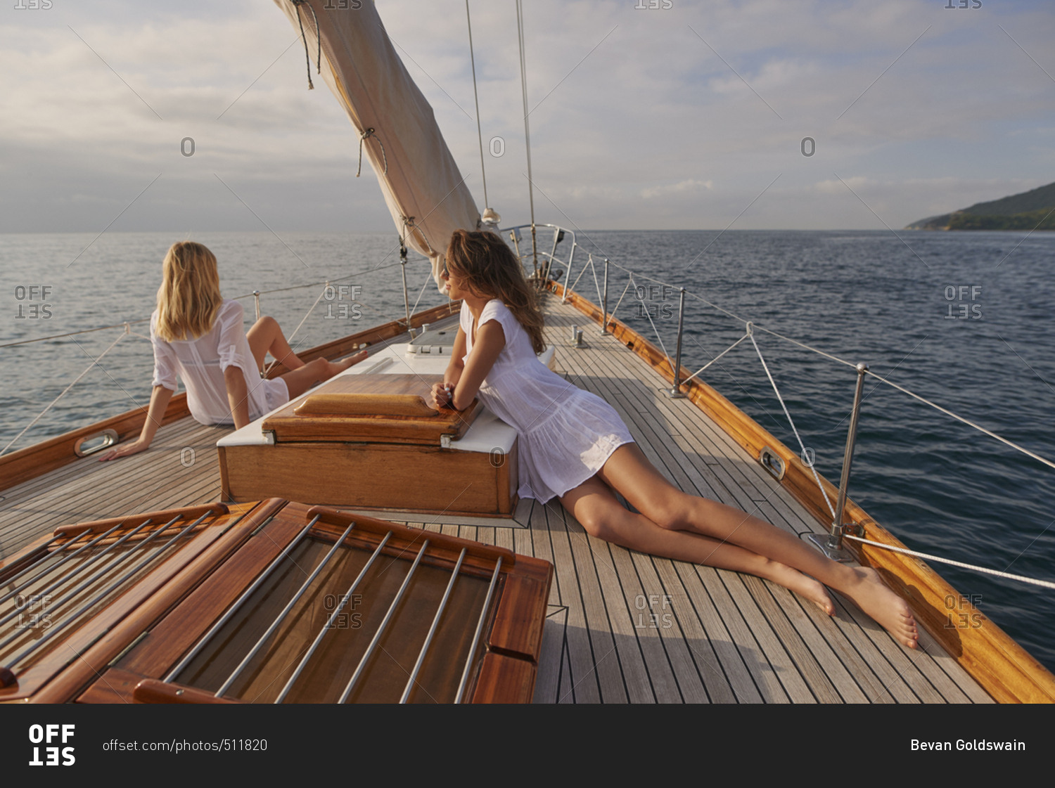 Beautiful girl friends on sailboat at sunset in ocean on luxury lifestyle happy adventure travel vacation