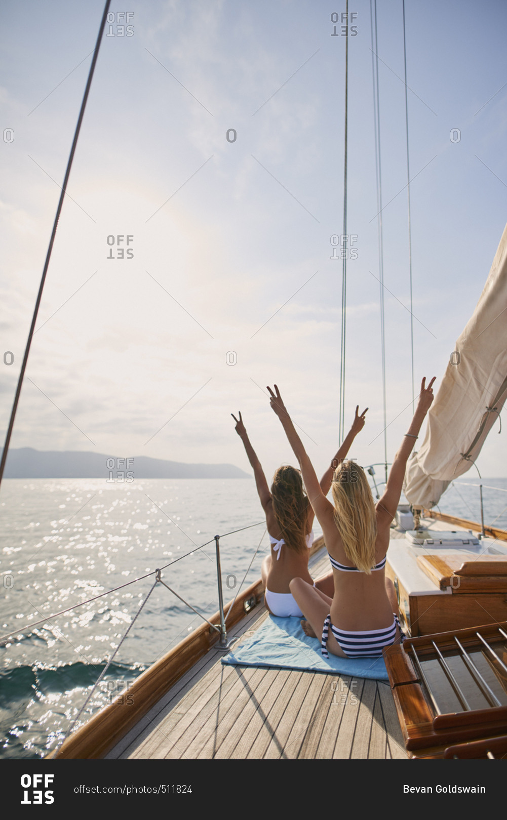 Beautiful women friends celebrate arms raised peace sign on sailboat in ocean on luxury lifestyle happy adventure travel vacation