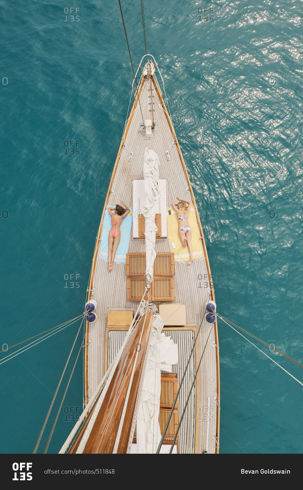 Beautiful girl friends tanning on sailboat in ocean from above overhead on luxury lifestyle adventure travel vacation