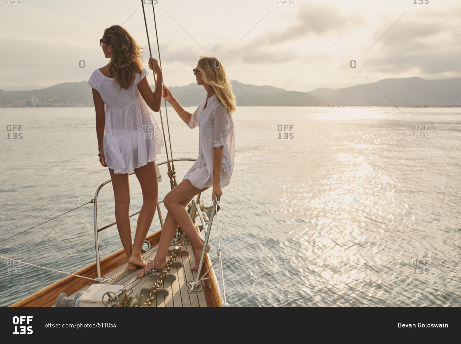 Beautiful girl friends on sailboat at sunset in ocean on luxury lifestyle happy adventure travel vacation
