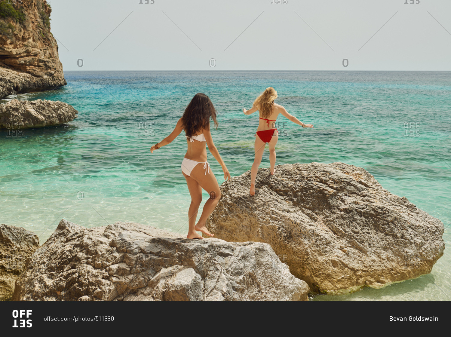 Beautiful girl friends rock jump on beautiful beach carefree wild travel adventure vacation