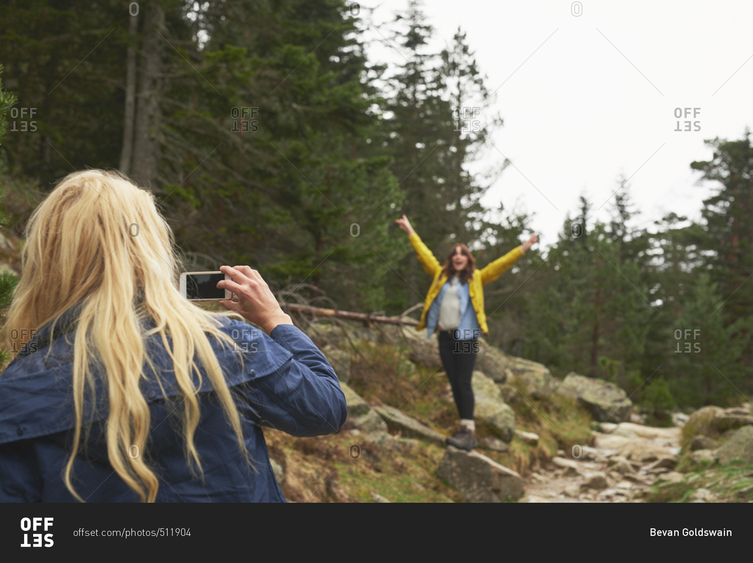 Girl taking photo of friend with smart phone for social media on travel adventure beautiful forest landscape