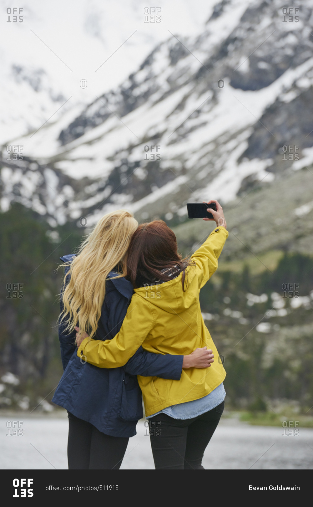 Travel adventure woman friends taking smart phone selfies on mountain lake enjoying beautiful nature landscape wanderlust