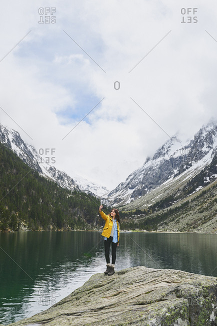 Travel adventure woman taking smart phone selfies on mountain lake enjoying beautiful nature landscape wanderlust