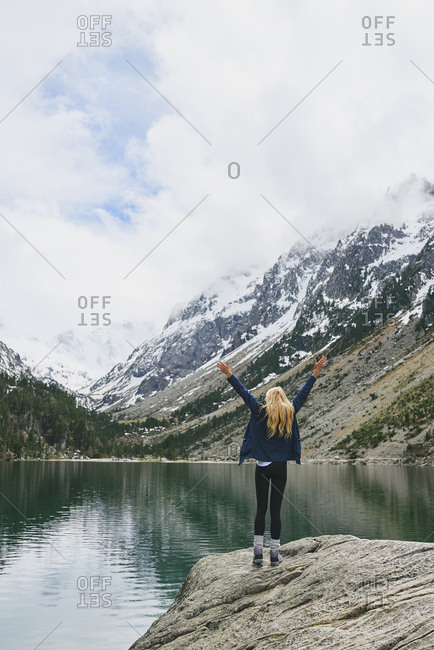 Travel adventure hiker woman celebrates on mountain lake arms outstretched enjoying beautiful nature landscape wanderlust