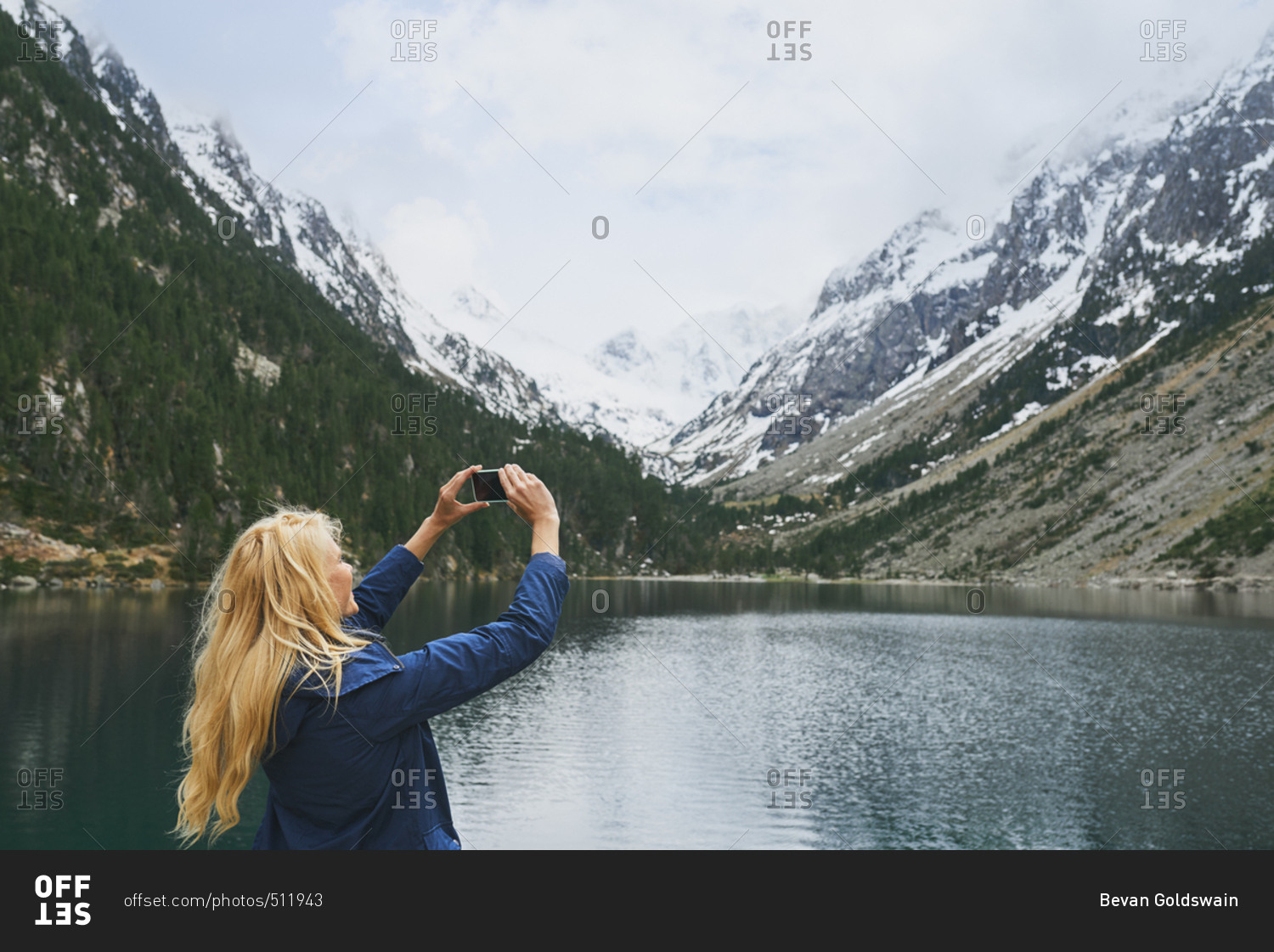 Travel adventure woman taking smart phone photograph on mountain lake enjoying beautiful nature landscape wanderlust