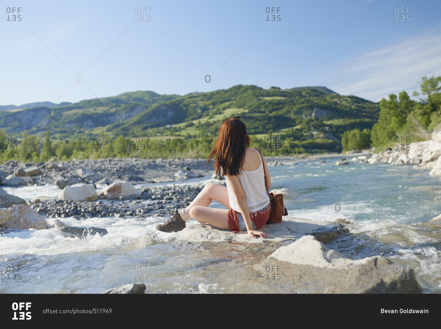 Travel adventure woman sitting on rock in river enjoying scenery view on vacation