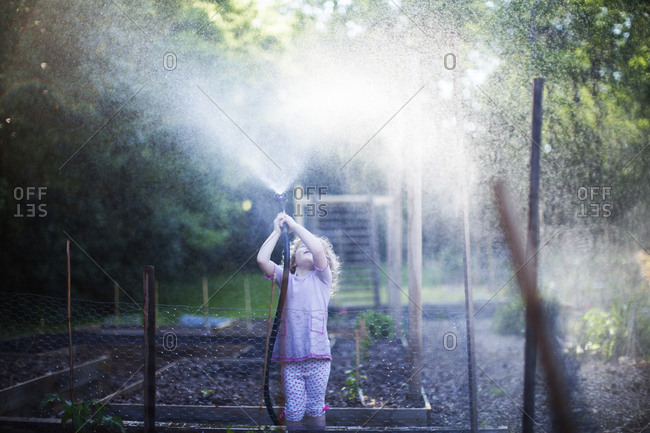 Girl playing with playing with garden hose