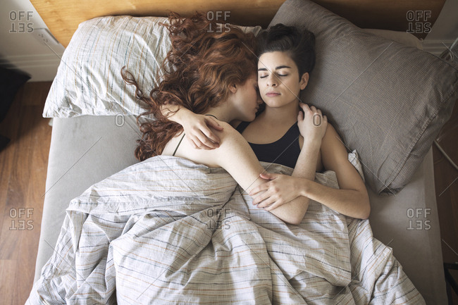 High Angle View Of Lesbian Couple Sleeping On Bed At Home