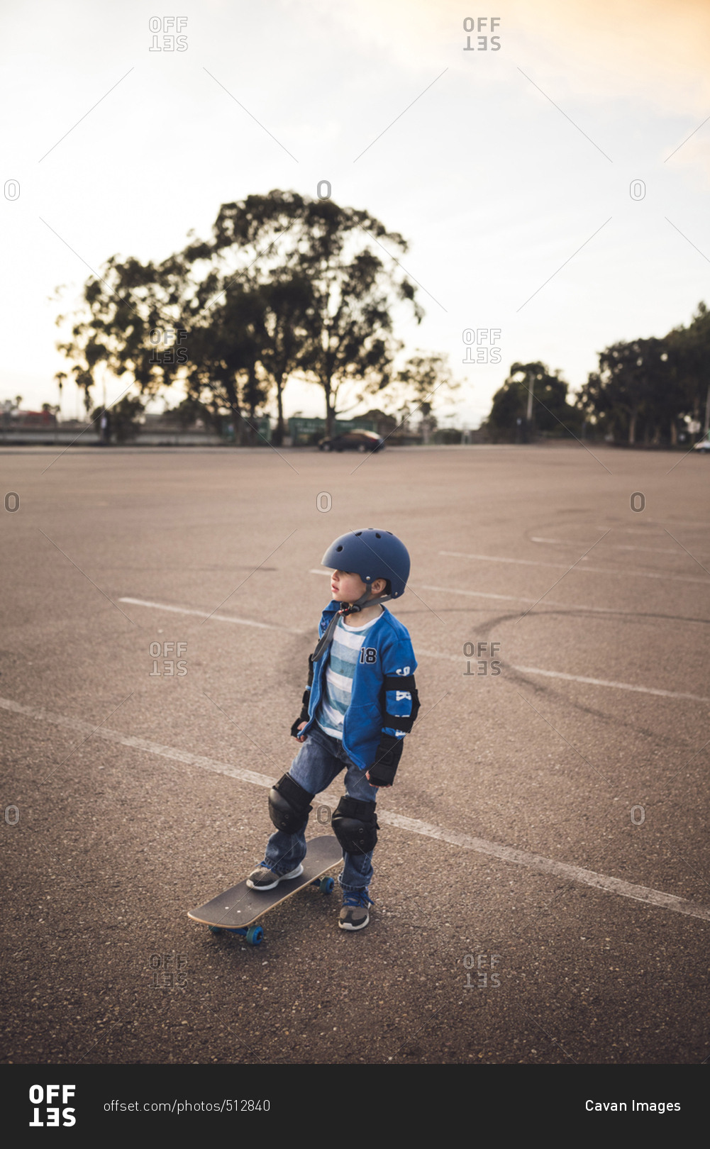 Boy standing with skateboard at field against clear sky