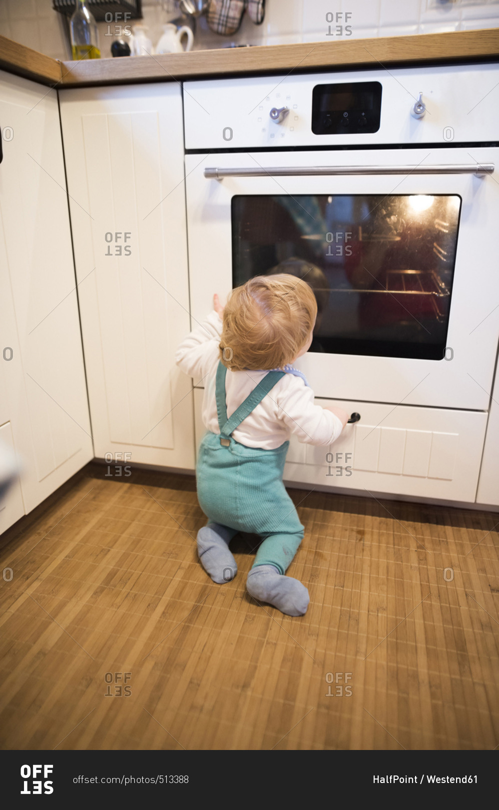 Baby boy sitting in kitchen watching cake baking in oven