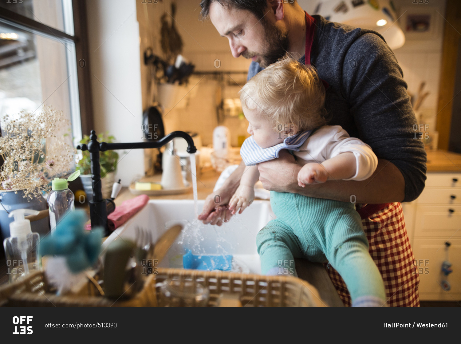 Father and baby boy in kitchen washing dishes