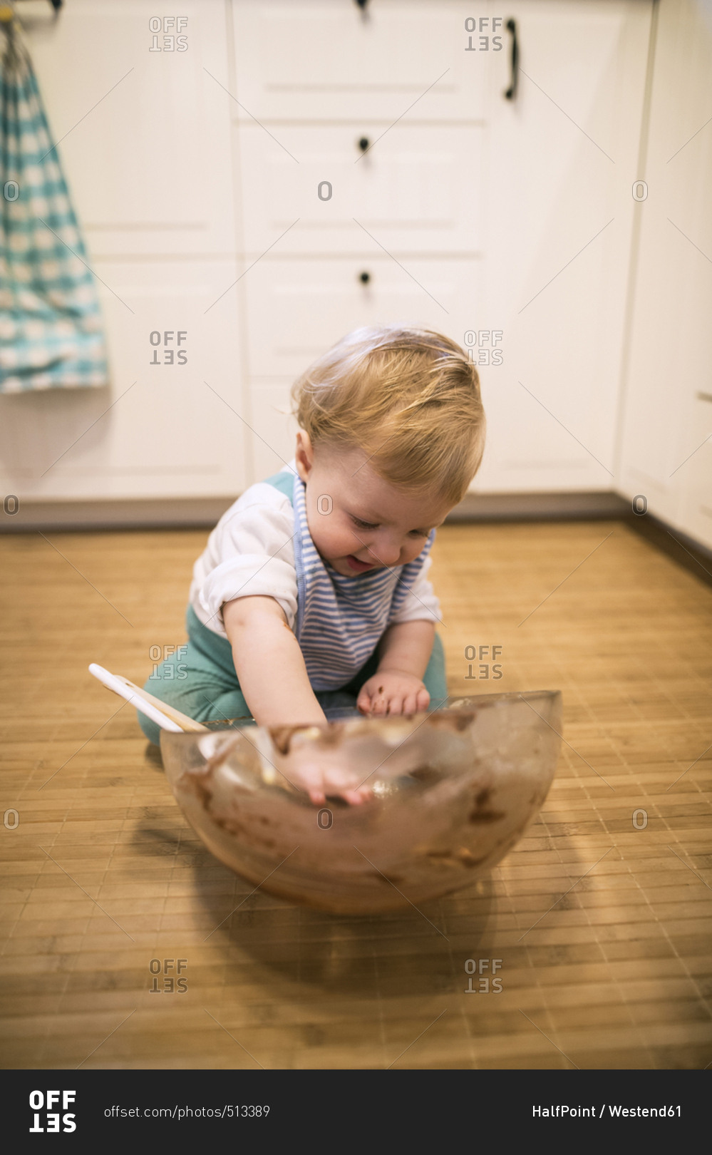 Baby boy sitting in kitchen nibbling cake dough