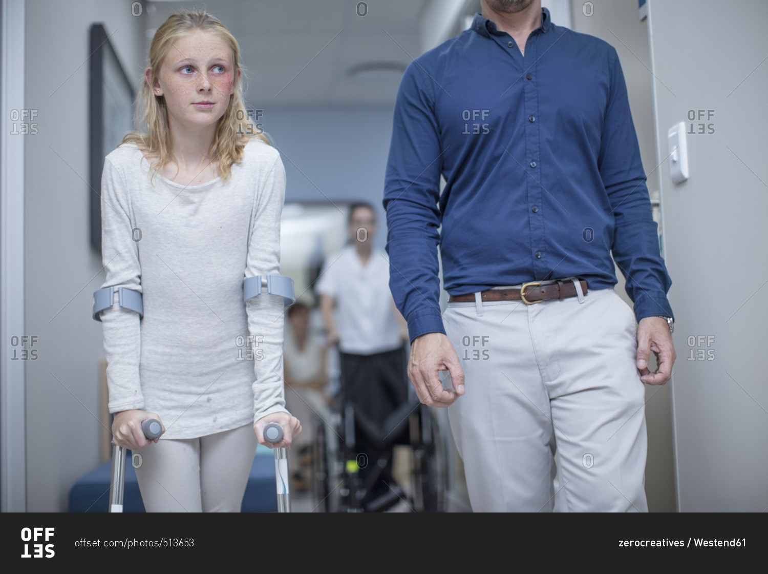 Girl with crutches walking with father in hospital
