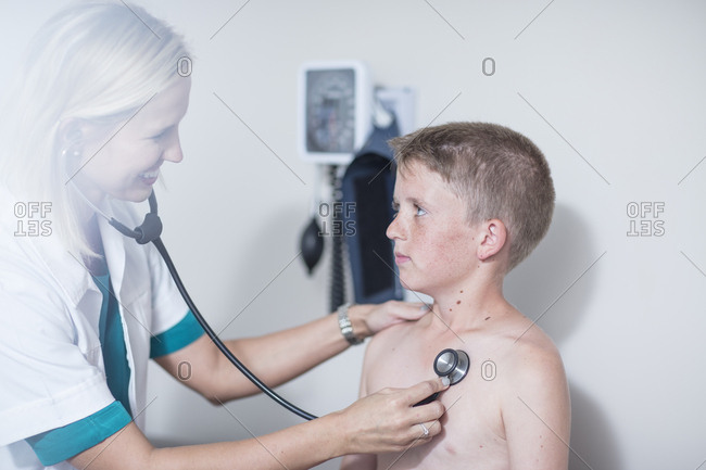 Female pedeatrician examining boy's lungs with stethoscope