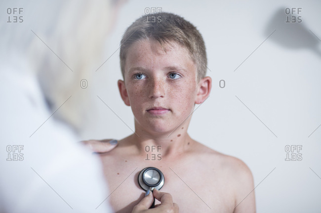 Female pedeatrician examining boy's lungs with stethoscope