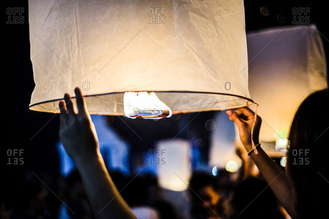 Young woman holding lit paper lantern waiting to release at Loy Krathong Paper Lantern Festival in Chiang Mai, Thailand