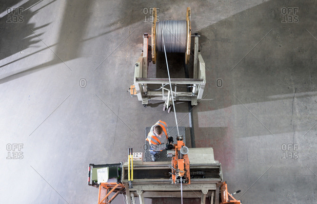 Worker winding electrical cables at cable storage facility, overhead view