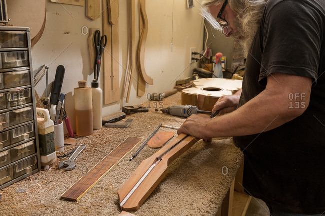 Guitar maker in workshop manufacturing guitar