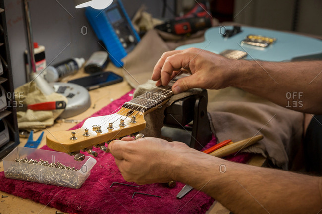 Cropped view of guitar maker's hands manufacturing guitar