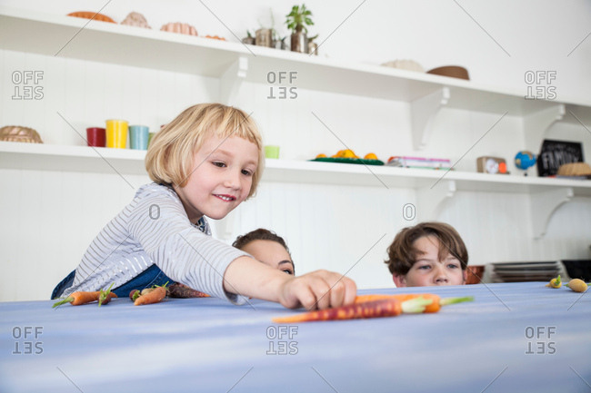 Young woman, boy and girl in kitchen, fooling around, peering over kitchen counter