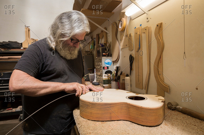 Guitar maker in workshop manufacturing guitar